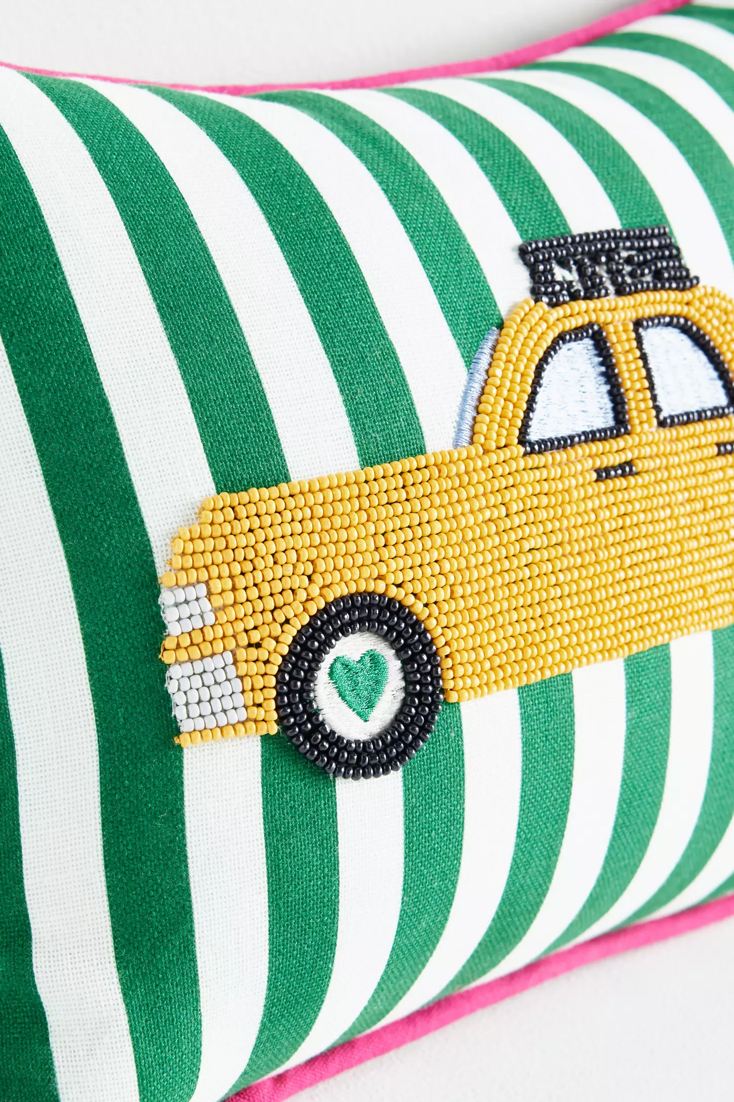 Green-and-white striped rectangular pillow with an embroidered yellow NYC taxi and pink piping on the edges.
