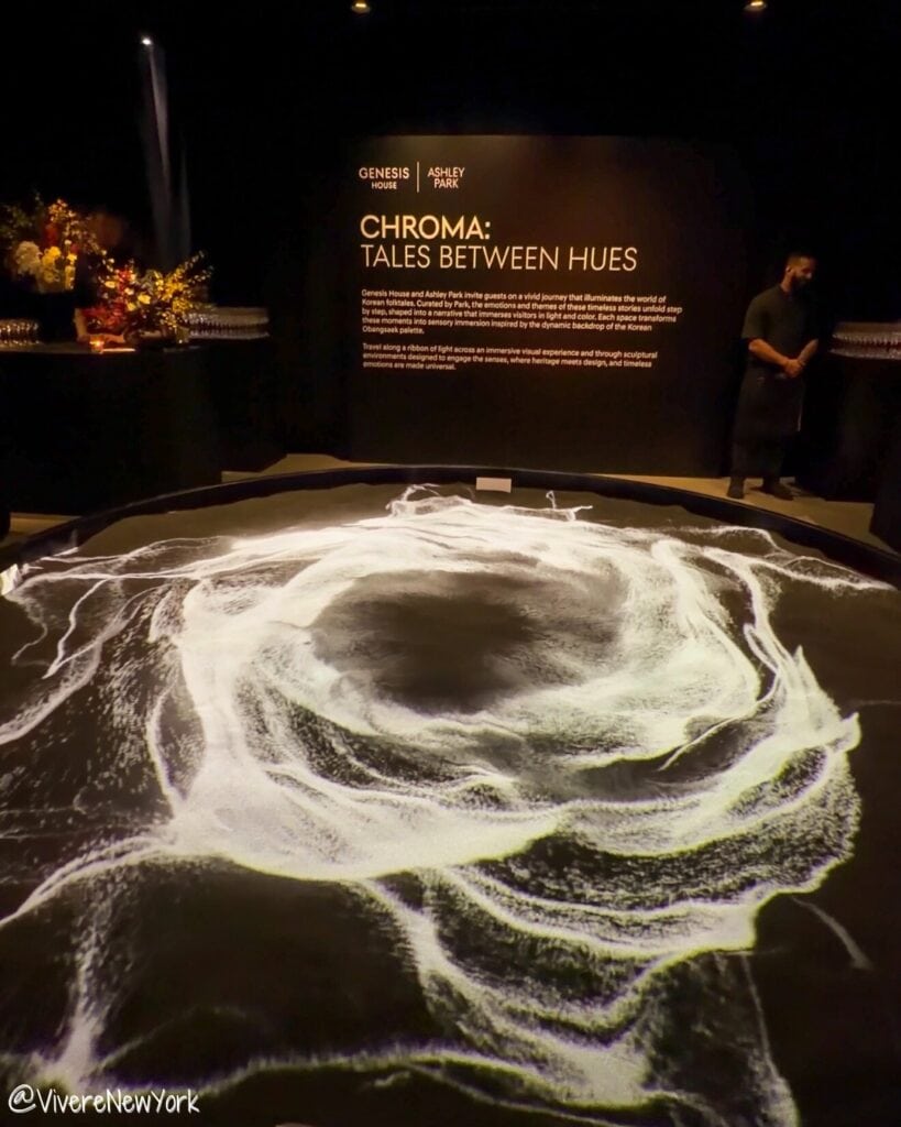 White-flower installation with circular projection transition room in CHROMA: Tales Between Hues at Genesis House NYC.