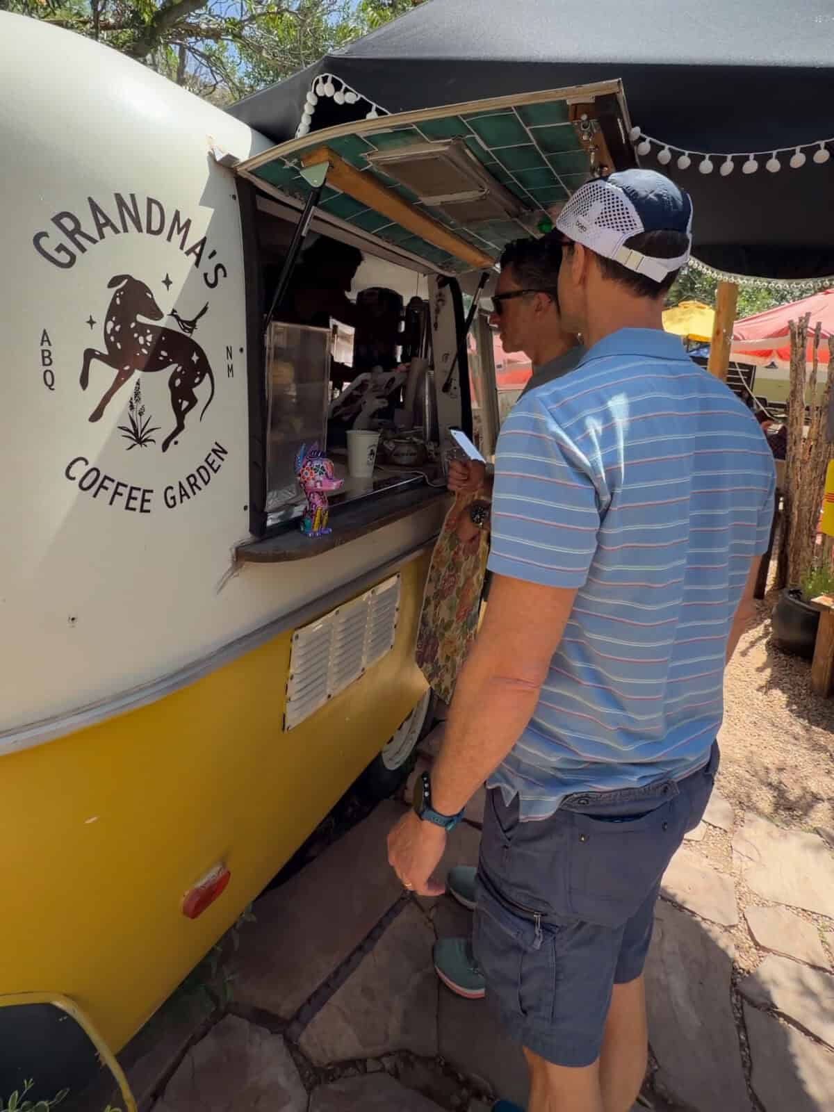 Luca and Massi ordering at the vintage camper window of Grandma's Coffee Garden, an outdoor coffee spot in Albuquerque