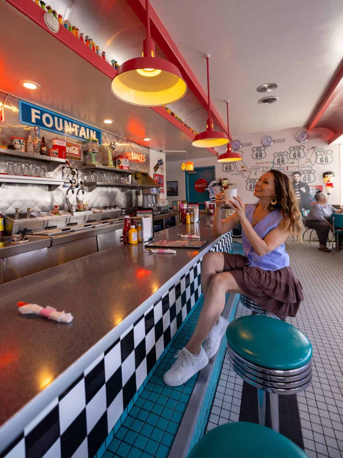 Laura with coffee at the retro soda-fountain counter inside the 66 Diner in Albuquerque