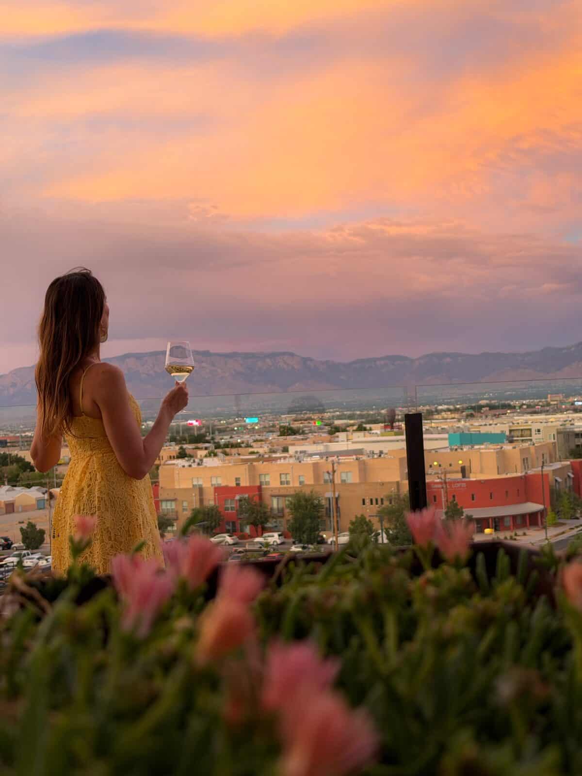 Laura watching the sunset over the Sandia Mountains with a glass of wine at Level 5 rooftop at Hotel Chaco in Albuquerque