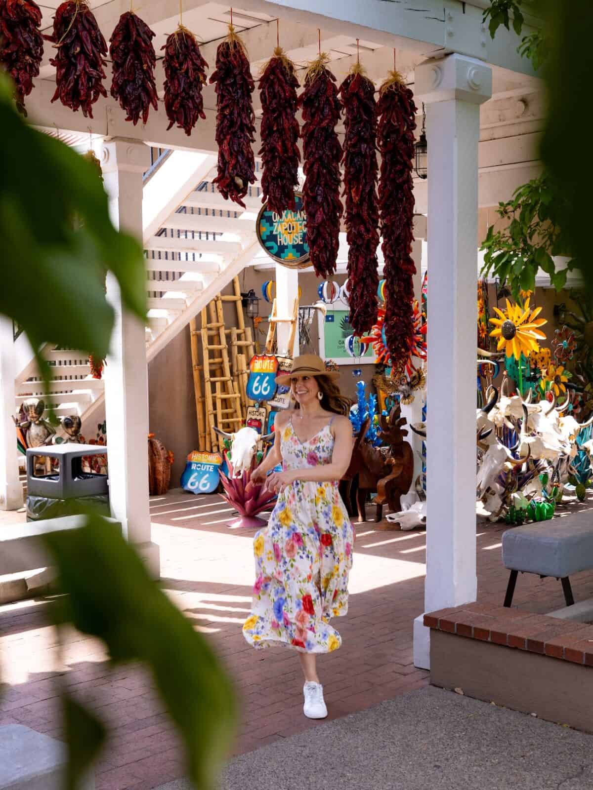 Laura walking beneath hanging red chile ristras in Old Town Albuquerque, New Mexico