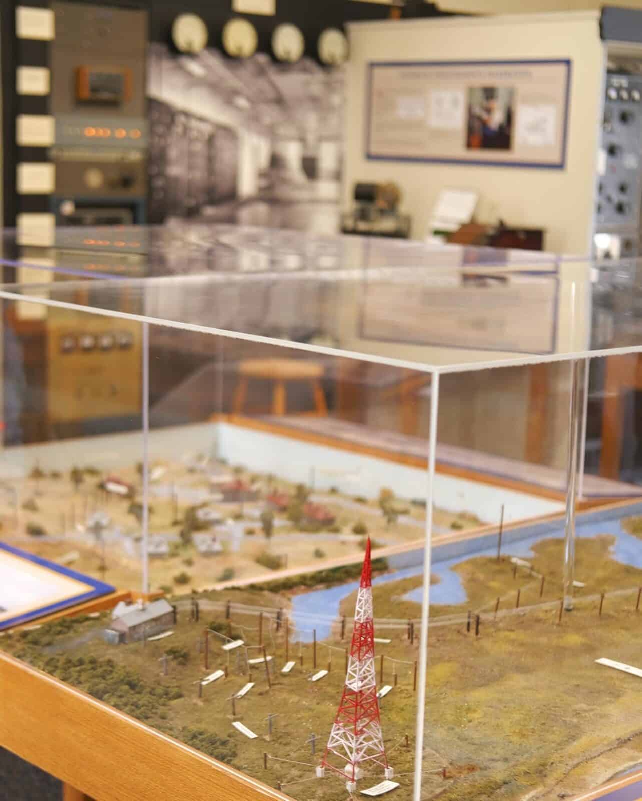 A detailed three-dimensional scale model inside a glass display case at the Chatham Marconi Maritime Center, depicting the historic Chatham Radio WCC antenna field with a miniature red and white radio tower and surrounding buildings.
