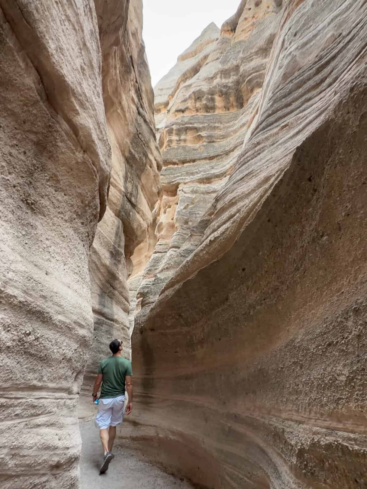 Luca walking through the towering smooth-walled slot canyon at Kasha-Katuwe Tent Rocks National Monument