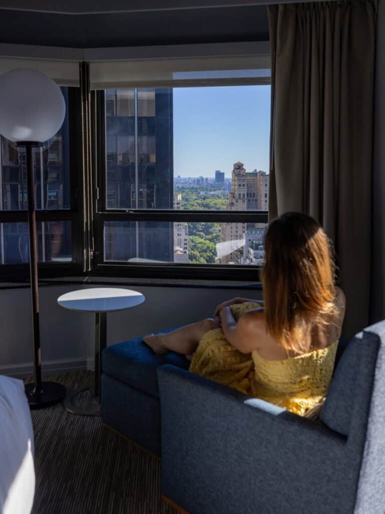 Laura sitting by the window of New York Hilton Midtown Room 3208 overlooking Central Park