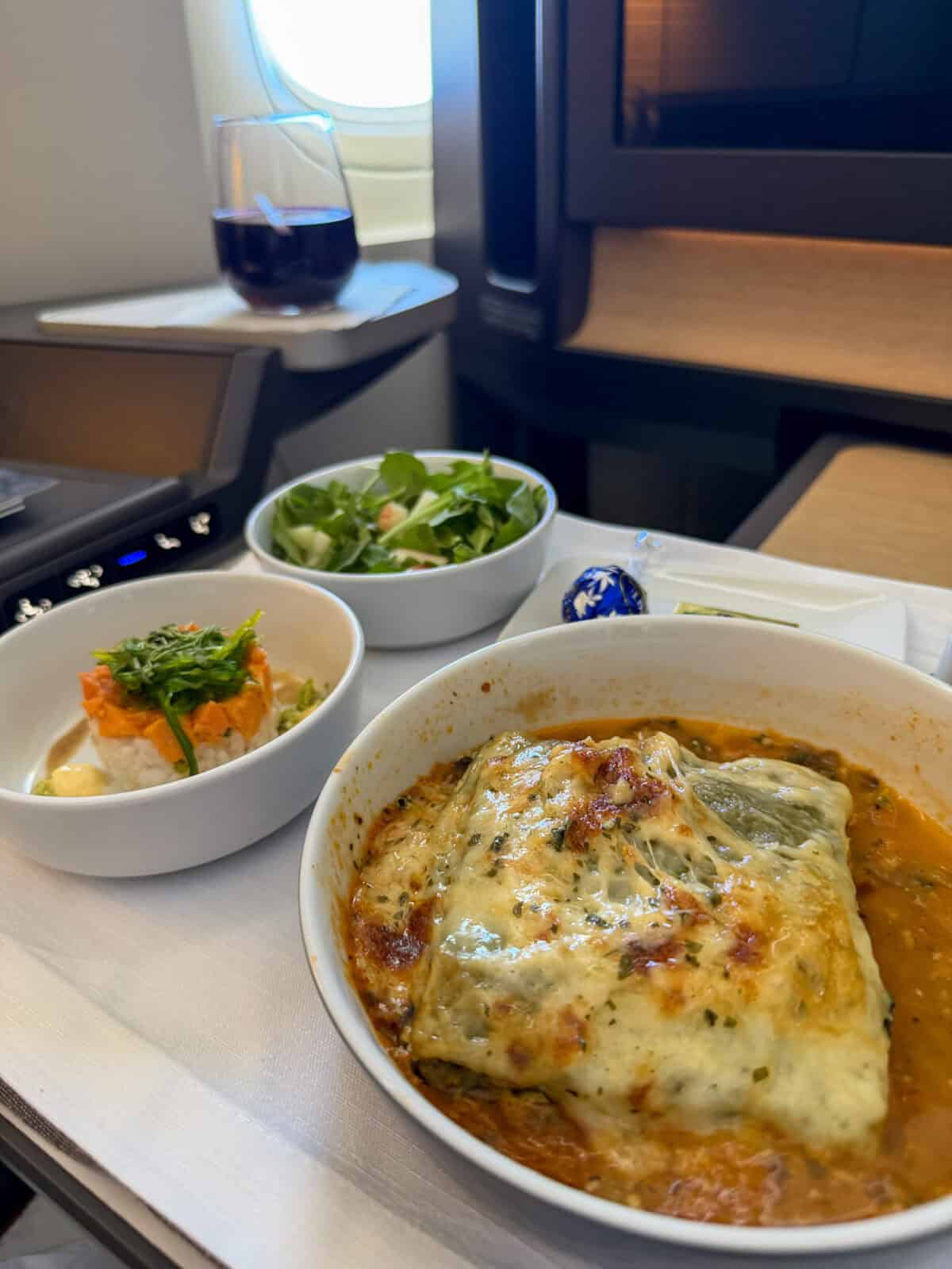 Vegetable lasagna served with salad and red wine in American Airlines Flagship Suite Business Class