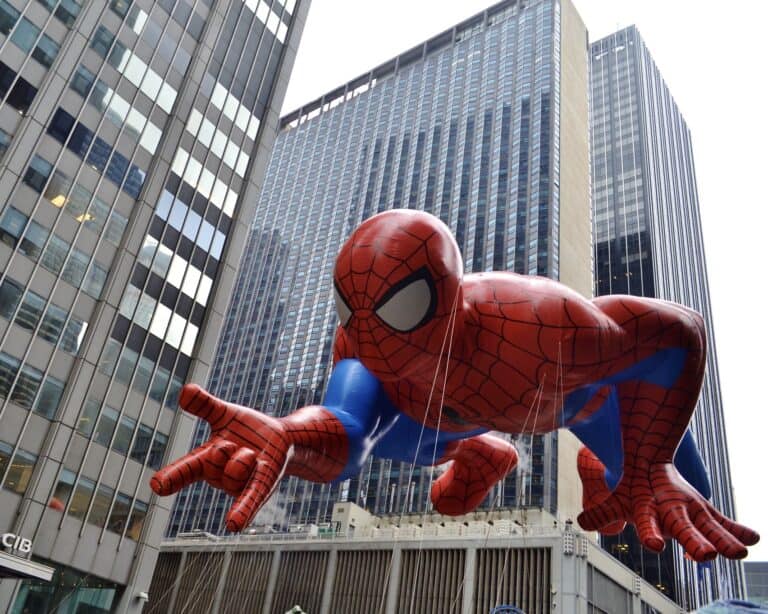 Giant Spider-Man character balloon floating between Midtown Manhattan skyscrapers during the Macy's Thanksgiving Day Parade